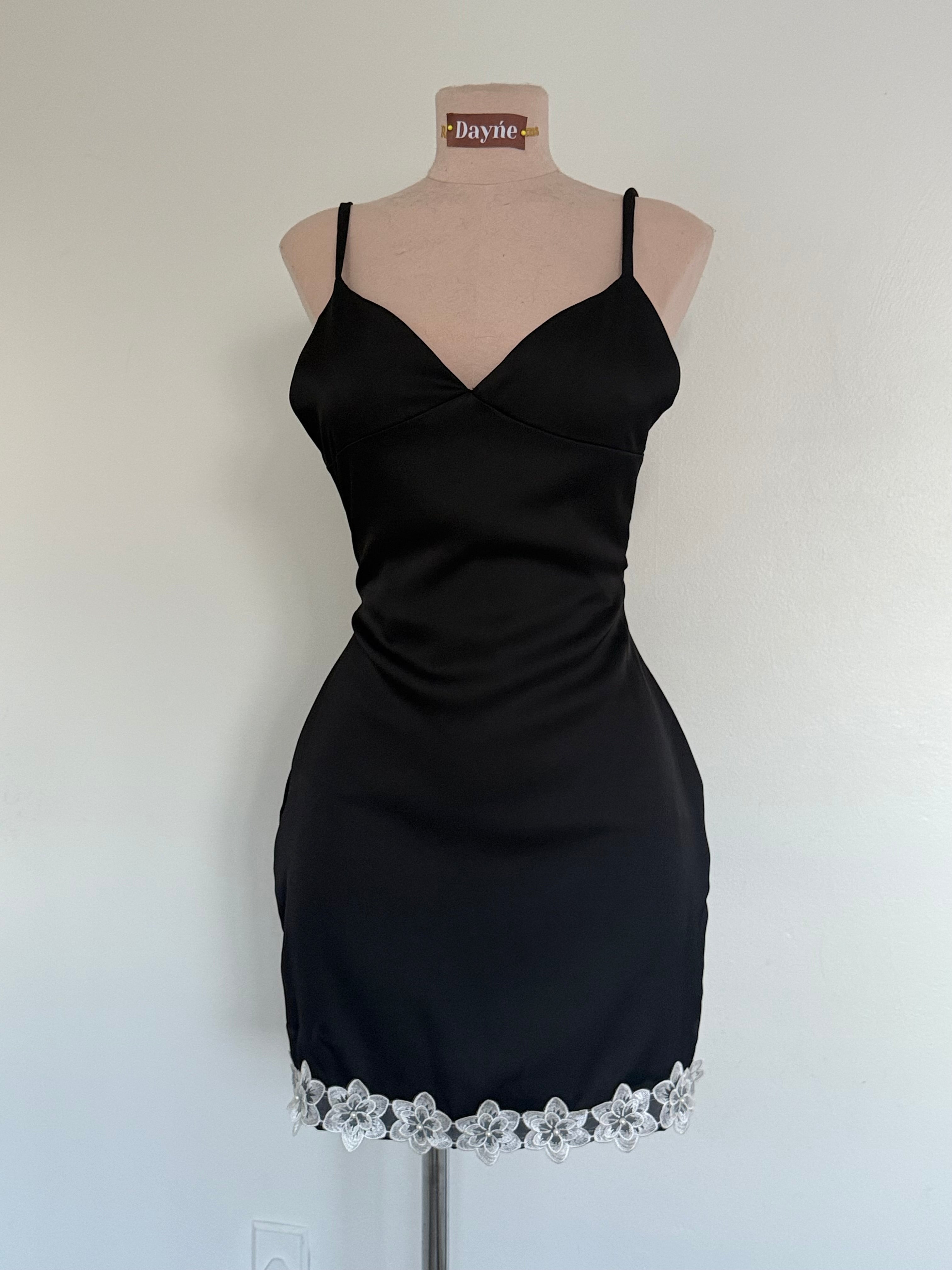 Black dress with floral lace hem on a mannequin against a white background