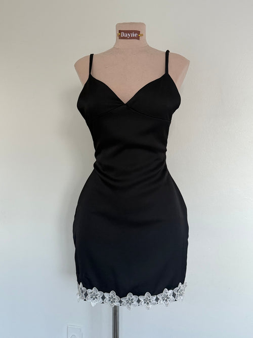 Black dress with floral lace hem on a mannequin against a white background