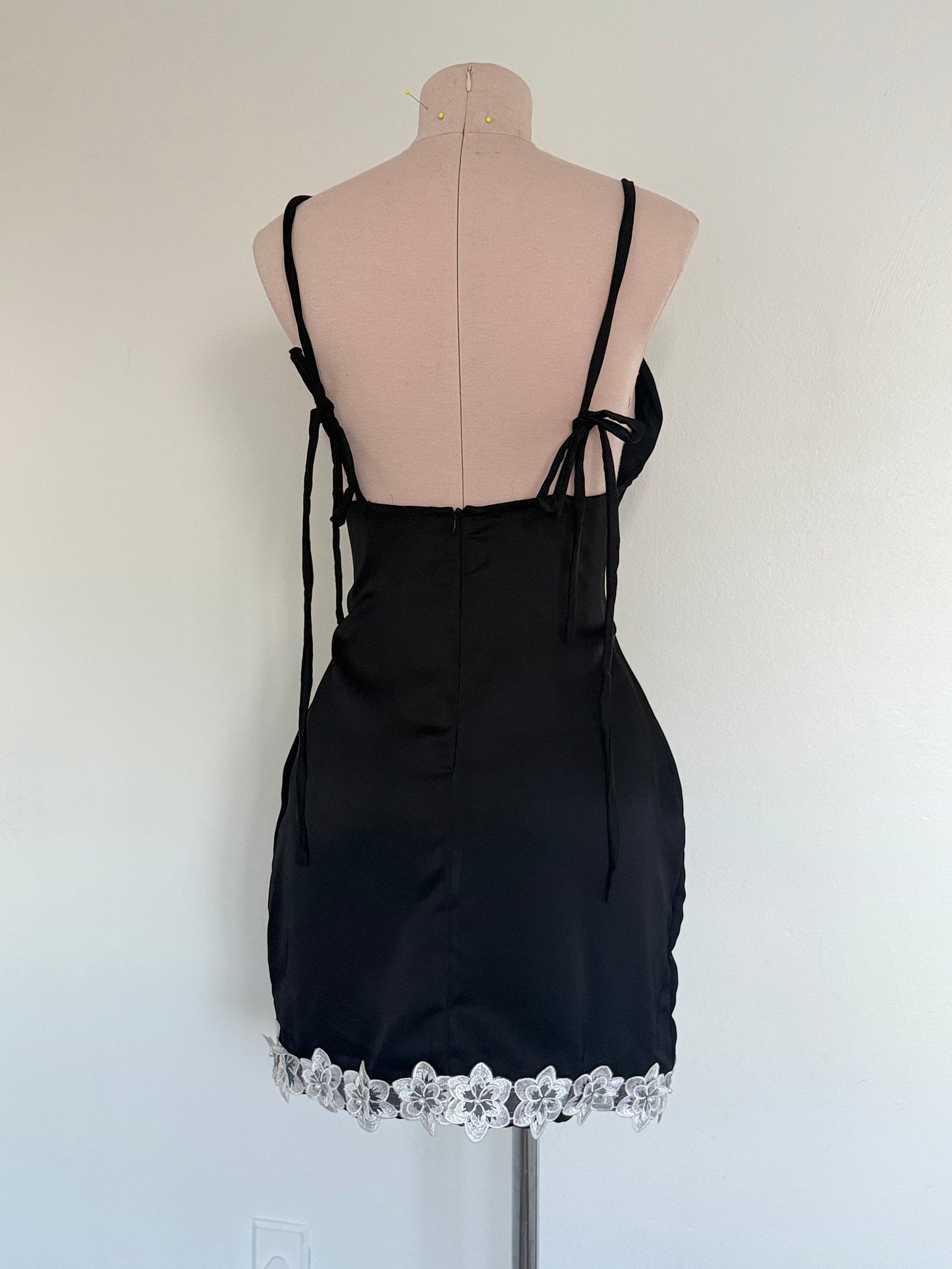 Black dress with lace hem on a mannequin against a white background