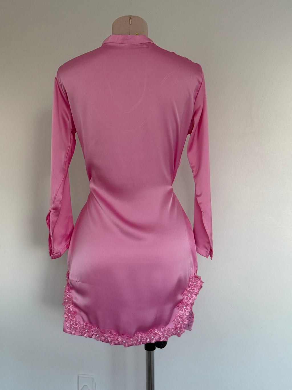 Pink dress with lace hem on a mannequin against a plain background