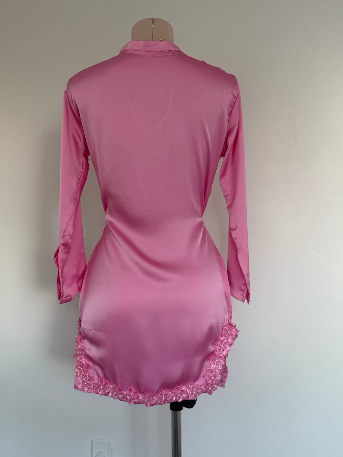 Pink dress with lace hem on a mannequin against a plain background